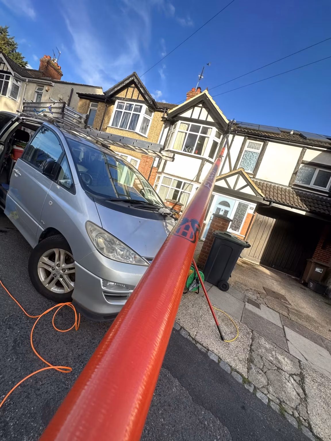 Window cleaner using a water-fed pole on terraced houses in Luton